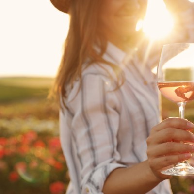 Woman,With,Glass,Of,Wine,In,Rose,Garden,On,Sunny