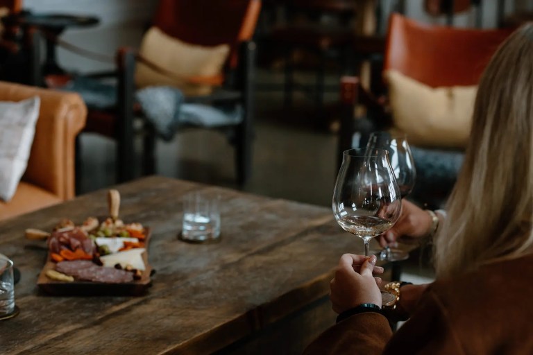 Guest enjoying a wine tasting with a charcuterie board in the tasting room