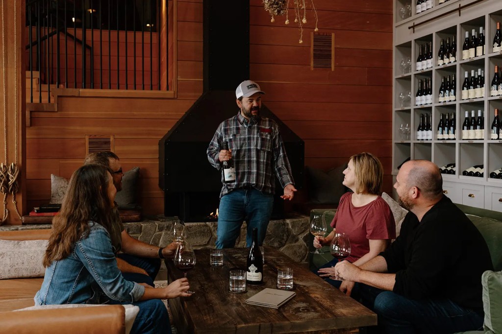 Wine educator leading a seated tasting experience for guests beside the fireplace