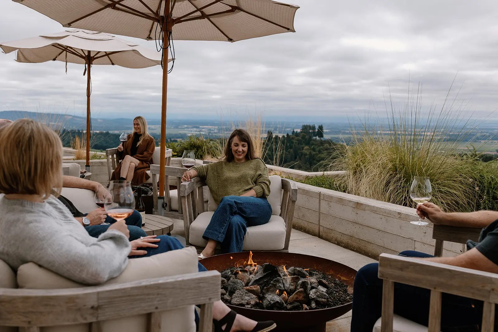 People drinking wine on a terrace next to a fire